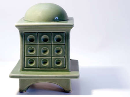 Miniature model of a green tiled stove on white background with shadowsの写真素材