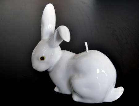 Easter decoration - white rabbit shaped candle on dark wooden tableの写真素材