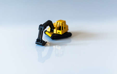 yellow toy excavator with great reflection on white backgroundの写真素材