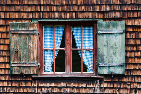 Idyllic Bavarian alpine cottage - window with curtains and wooden panelsの写真素材