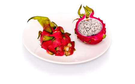Two halves of pitahaya or dragon fruit on a white plate with shadow and reflection on white backgroundの写真素材