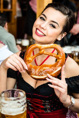 Woman in Dirndl eating Oktoberfest Pretzelの写真素材