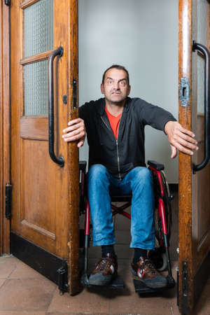 Man in wheelchair stuck between swing doorsの写真素材