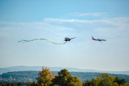 A colorful kite is being overtaken by an airplane approaching Stuttgart airport in Germanyの写真素材