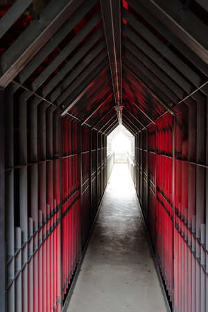 Mysterious dungeon tunnel with walls made of metal lit redの写真素材