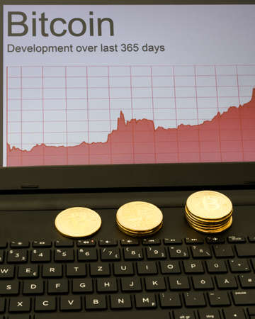 Bitcoins and rising chart on laptop computer