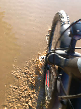 Mountain bike cyclist riding on a wet and muddy roadの写真素材