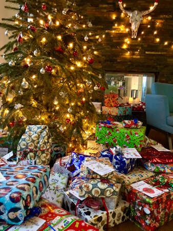 Christmas Tree and lots of Christmas gift boxes interior with fireplaceの写真素材