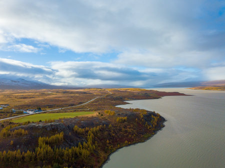 Aerial of a lake near Egilsstadir, Iceland, showcasing a sprawling plain with majestic mountains rising in the backgroundの写真素材