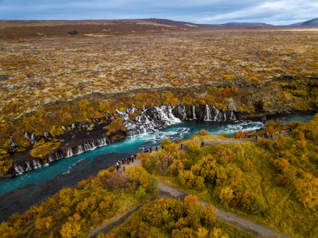 Tourists marvel at the stunning waterfalls from a nearby path, soaking in the beauty of the...