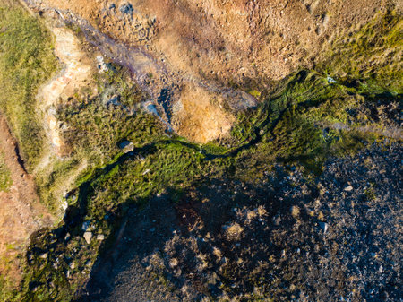 Aerial perspective of a geothermal river meandering through a colorful terrain, highlighting the unspoiled allure of icelands natural environmentの写真素材