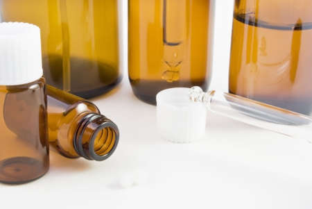 A collection of amber glass bottles (spray, dropper and pill) and pillules used in homoeopathic pharmacy.の写真素材