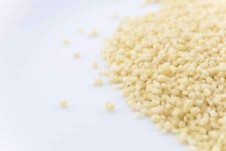 Macro (close-up) of couscous grain scattered on right side of frame.  White copy space to the left.の写真素材