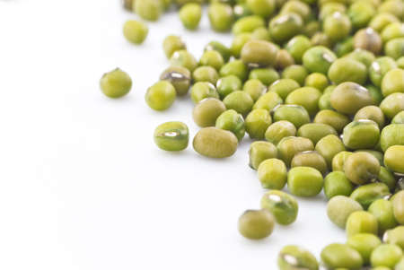 Macro (close-up) of green mung beans, scattered on right side of frame.  Isolated with white copy space to the left.  Horizontal (landscape) orientation.の写真素材