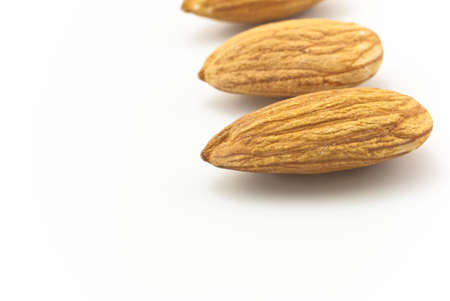 Three shelled almonds, in a row in right half of frame, on white background, with shadows.  Copy space to left.の写真素材