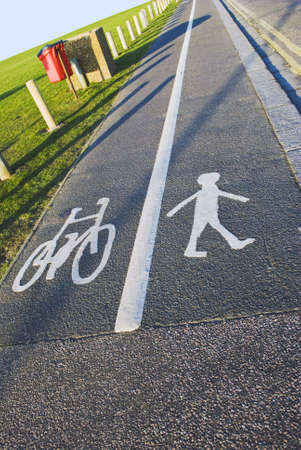 A British pavement, divided and signed for cyclists and pedestrians between an open field and a...