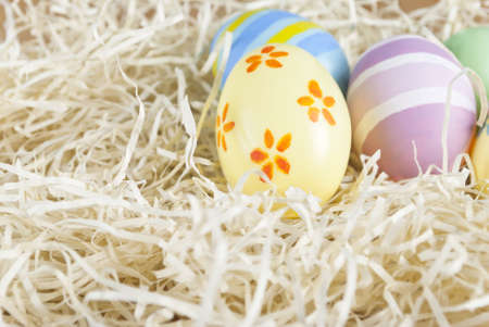 Handpainted Easter eggs situated in upper right portion of frame, in a simulated straw nest of shredded paper.の写真素材