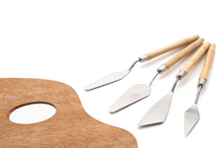 A traditional wooden artist's palette beside a set of palette knives for oil painting.  Isolated on a white background with soft shadows retained.の写真素材