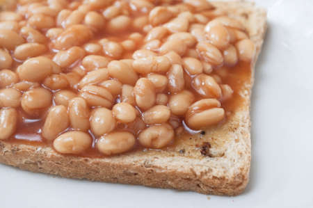 Cooked baked beans on wholemeal granary toast shot in close up and cutting off at left frame.  Plate showing to right and below.の写真素材