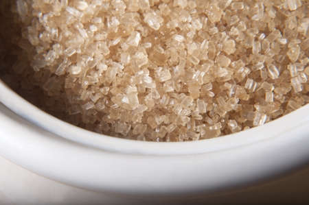 Close up (macro) of granulated brown sugar (demerera) in a cream coloured china bowl.の写真素材