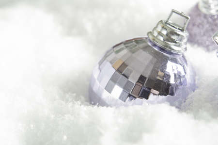 A lilac (light purple) Christmas bauble partly submerged in fake snow.  Snowy surface provides copy space to left and beneath the ornament.の写真素材