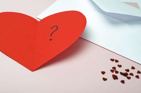 A red heart-shaped Valentines card, opened to reveal a question mark.  Small metallic hearts...