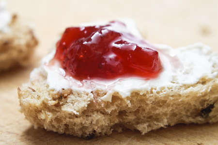 A heart shaped piece of bread topped with cream cheese and strawberry jam on a wooden surface.の写真素材