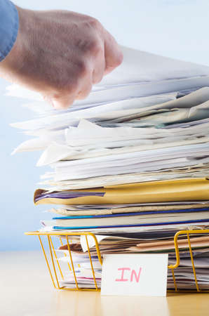 Business image of a male hand with blue shirt cuff visible, adding or removing document from tall...