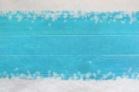 Christmas snow and snowflakes border at top and bottom of light, bright blue wood planking.の写真素材