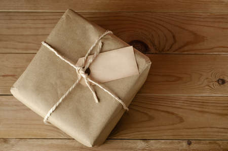 Overhead shot of a brown paper parcel, tied with string.  Blank label faces upwards to provide copy...