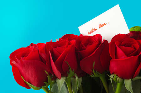 A bouquet of red roses against sky blue background.  A white message card shows 'With Love' in red...
