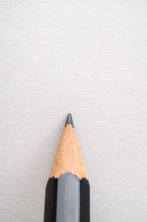 A graphite pencil, poised as if about to write or draw on blank white paper.の写真素材