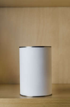 One single tin can (aluminum) with blank white label on shelf in an otherwise empty kitchen cupboard.の写真素材