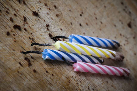 Close up of four used, striped  birthday cake candles, burned out and lying grouped amongst...