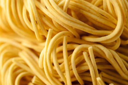Close up (macro) of dry, uncooked egg noodles, curling and intertwined. Shallow depth of field.の写真素材