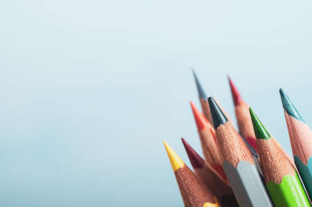A selection of art pencils in different colours, grouped at lower right of frame with pale blue background providing copyspace to left and above.の写真素材
