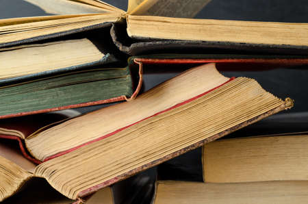 Close up of a pile of old text books, opened as if study in progress, stacked untidily with...