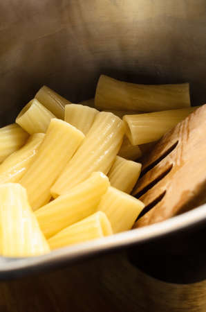 Freshly cooked and drained hot pasta (Rigatoni) in stainless steel saucepan with wooden spatula.の写真素材