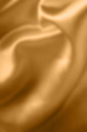 Yellow golden coloured satin fabric, draping with soft folds. Blurred background.の写真素材