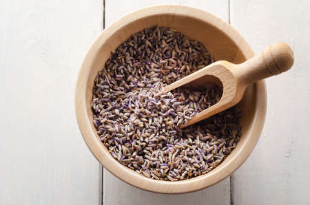 Overhead view of a wooden bowl and scoop, filled with dried lavender herb flower buds.の写真素材