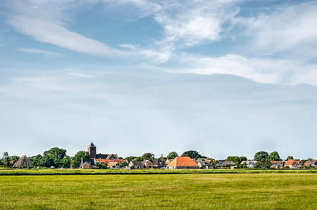 Island of Texel, The Netherlands, July 21, 2018: The village of Oosterend in green fields under a predominantly blue summer skyのeditorial素材