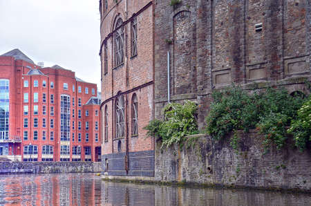 Bristol, England, June 2, 2014: bushes growing out of the wall of the old brick facades of warehouses built directly against the waterのeditorial素材