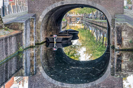 Edam, The Netherlands, October 7, 2018: two sloops moored under the brick arch of the bridge across Voorhaven canal at Dam squareのeditorial素材