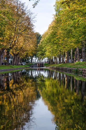 Edam, The Netherlands, October 7, 2018: Lines of trees in autumn colors on both sides of the IJe canal, relfecting in the calm water on a beautiful day in Octoberのeditorial素材