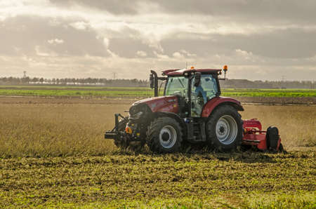 Noordoostpolder, The Netherlands, October 24, 2018: Agricultural machine ploughing up a field in an...