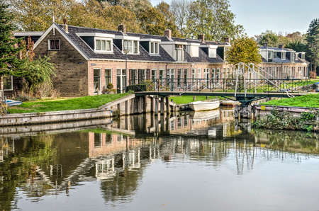 Bolsward, The Netherlands, November 4, 2018: pedestrian bridge across a canal lined with small laborer's cottages just outside the historic town centerのeditorial素材