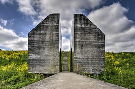 Culemborg, The Netherlands, April 8, 2018: the sawed through bunker 599, monument of the Dutch water line inundation system, placed in the slope of a dike with grass and rapeseedのeditorial素材