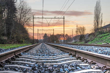 View between the two steel bars of a railroad track diminishing in the distance, in the Dutch...