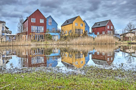 Culemborg, The Netherlands, March 4, 2018: colorful wooden scandinavian-style houses reflecting in a pond in experimental and ecological Lanxmeer neighbourhoodのeditorial素材