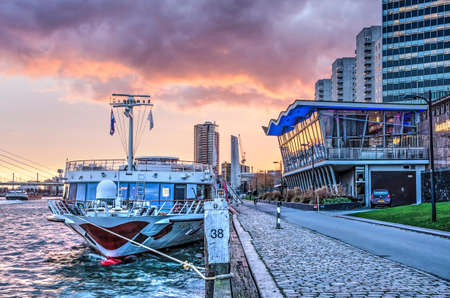 Rotterdam, The Netherlands, December 4, 2018: river cruise ship moored near the Boompjes pavillion under a colorful sky at sunsetのeditorial素材